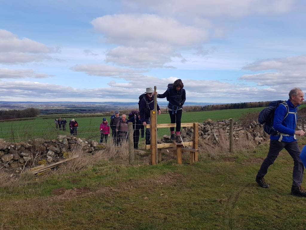 Walkers climbing over a stile